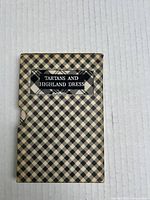 Book titled 'Tartans and Highland Dress' in black and beige checkered slipcover.