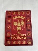 Front cover of 'The Paisley: Thread' book showing red cover with gold embossed crest and title.