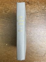Photo of the book spine with title and author embossed in gold on grey cloth binding.
