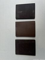 Three vintage hardback books with plain brown covers stacked on a white surface.