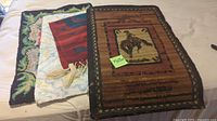 Stack of three rugs showing floral, striped flatweave, and cowboy pictorial pieces