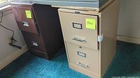 Beige and brown steel 2-drawer filing cabinets side by side under tabletop