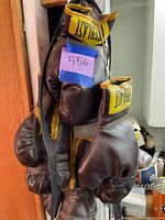 Front view showing multiple pairs of Everlast gloves hanging, visible yellow labels and taped wrist on one glove