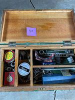 Open wooden machinist chest with visible tins, tools and goggles