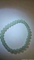 Top-down photo of the green aventurine bracelet showing the full circular arrangement of beads on a plain background.