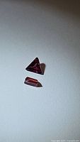 Two natural red pink sapphires placed on white background, one triangular cut and one rectangular cut.