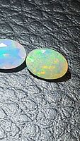 Pair of natural Ethiopian opals on black textured background showing vivid play of color