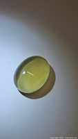 Top view of lemon citrine oval cabochon shows smooth polished dome with light reflection.