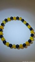 Clear image of round yellow agate and black onyx beads on stretchy bracelet forming a circular shape on white background.