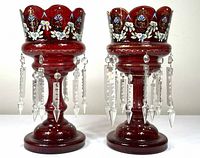 Front view of both cranberry glass lustres showing enamel decoration and prisms