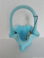 Top view of blue frosted Fenton glass basket with its ruffled edge and handle visible