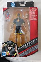 Full front view of The Flash action figure in black and yellow costume with alternate head and red/blue accessory figure, in unopened packaging with some wear on the box.