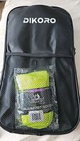 Full view of the black Dikoro branded carrying case with mesh pocket containing the yellow ankle sleeves and other items inside.