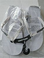 Photo showing the pair of white Jack & Jones flip flops in original clear plastic bag with printed instructions, size tag and branded hanger.