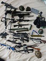 Wide view of all G.I. Joe accessories including guns, helmets, ammo belts, and bags spread on a bed.