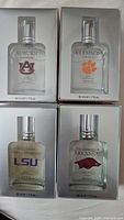 Front view of four boxed Masik collegiate fragrances for Auburn, Clemson, LSU, and Arkansas showing university logos and bottle designs.