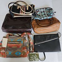 Lot of six purses displayed on a white surface showing variety in style, color, and material
