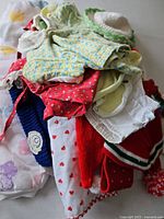 Pile of assorted vintage baby clothes showing various colors, fabrics, and patterns including knits and cotton.