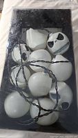 String lights with white Jack Skellington heads laid on a surface inside original box