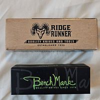 Closed Ridge Runner and BenchMark pocket cutters in their original boxes shown from top view.