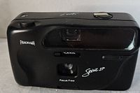 Front view of the black Panorama Spirit SP camera showing the lens, viewfinder, and panoramic feature in matte black plastic body.