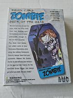 Front of the sealed game box showing title and artwork with zombie holding a skull in a graveyard scene
