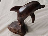 Front angle of dark polished wooden dolphin carving on base