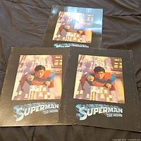 Three Superman The Movie promotional brochures laid out on a brown surface, showing the classic flying Superman cover image.