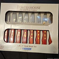 Photo of the 8-piece Tramontina Porterhouse steak knife set in original packaging, showing serrated blades and wooden handles with brass rivets