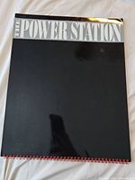 Front cover showing "THE POWER STATION" title on black background with spiral binding along bottom edge.