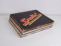 Stack of 17 assorted vintage vinyl LP records including Humble Pie 'Smokin' with visible wear on edges of sleeves.