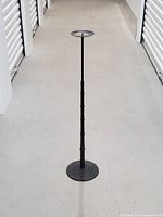 Full view of the candle holder standing on concrete floor in a storage facility hallway showing its height and slender design.