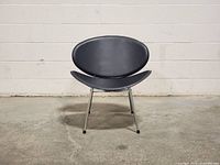 Front view of the black Jacobsen style chair showing curved oval backrest and seat with chrome legs.