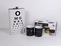Photo showing the oversized white stainless steel flask with eye chart text beside the boxed set of three Chuzy Chef color changing mugs.