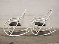 Side view of both white metal vintage rocking chairs with black cushions showing full profile and seat height.