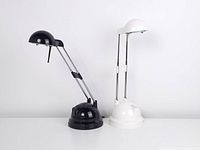 Photo showing both black and white vintage Ikea Espressivo halogen telescoping desk lamps at angled view with arms extended