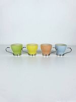 Front view of 4 Vitrosax espresso cups in green, yellow, peach, and blue pastel colors arranged in a row.
