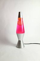 Full view of the vintage lava lamp showing the pink liquid and red wax inside a silver metal base and cap, with the power cord visible.