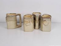 Four vintage Rodolpho Padilla ceramic stoneware mugs shown from an angle showcasing the drip glaze and swirl design.