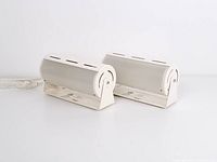 Pair of two vintage Ikea Smyg wall lamps shown from a side angle, displaying cylindrical white metal tubes with attached cords and inline switches.