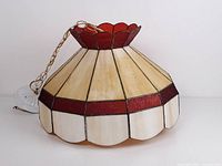 View of the stained glass pendant lamp showing red and white glass panels with scalloped red top edge and hanging chain.
