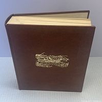 Brown hardcover book standing upright showing front cover with gold embossed horse-drawn wagon illustration.
