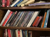 Horizontal bookshelf with multiple shelves filled with books, magazines in sleeves, and other documents.