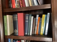 Bookshelf wood grain and texture with several hardcover books arranged vertically, including dictionaries and classic literature.