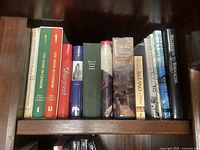 Photo of wooden bookshelf shelf holding 14 books primarily about history, culture, and wildlife.