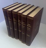 Seven volumes of the Grolier Encyclopedia standing upright showing spine titles and volume numbering