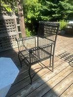Full view of one black wrought iron patio chair on deck