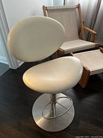 Front view of white oval-back salon chair with chrome base