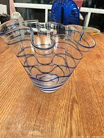 Full view of flared glass vase showing blue swirl stripes and ruffled rim