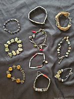 Group shot of all ten bracelets laid out on dark fabric